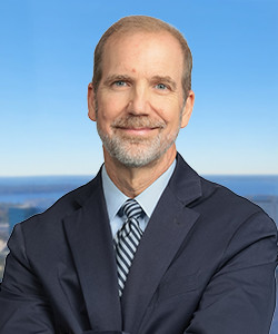 Professional portrait of a middle-aged man with a beard and blue suit.