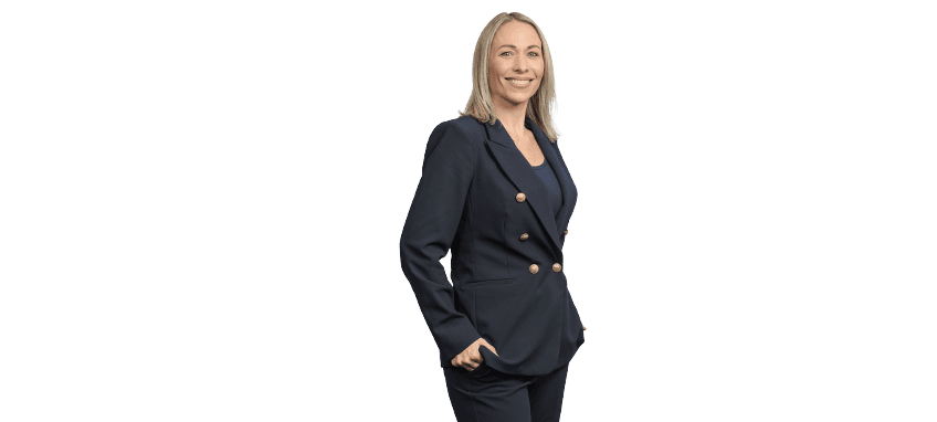 Professional woman in navy blazer smiling with hands in pockets.