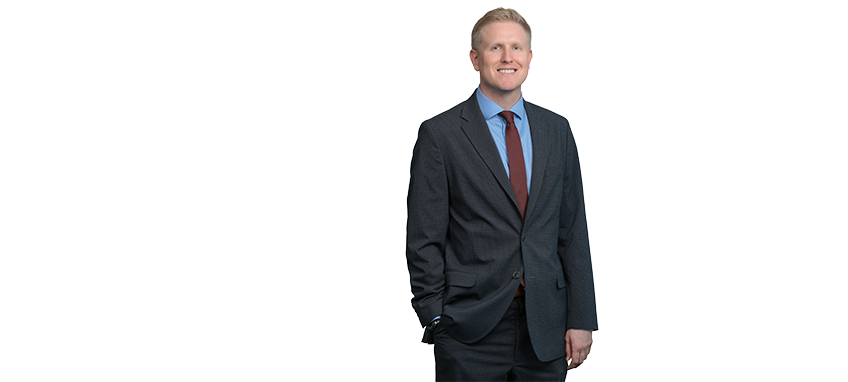 Smiling man in a suit with hands in pockets.