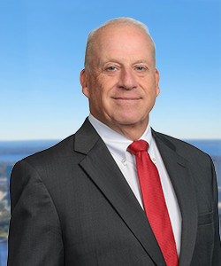 Portrait of a smiling man in a suit with a blue sky background.
