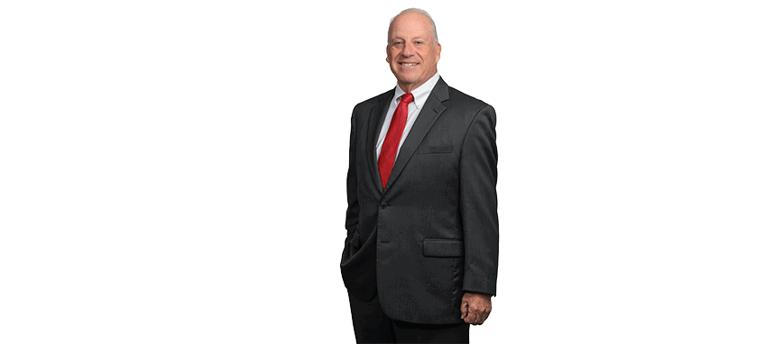Man in a dark suit with a red tie smiling at the camera.