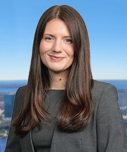 Professional portrait of a woman with long brown hair in a gray blazer.