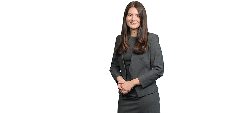 Professional woman with long brown hair in a gray blazer and black top.